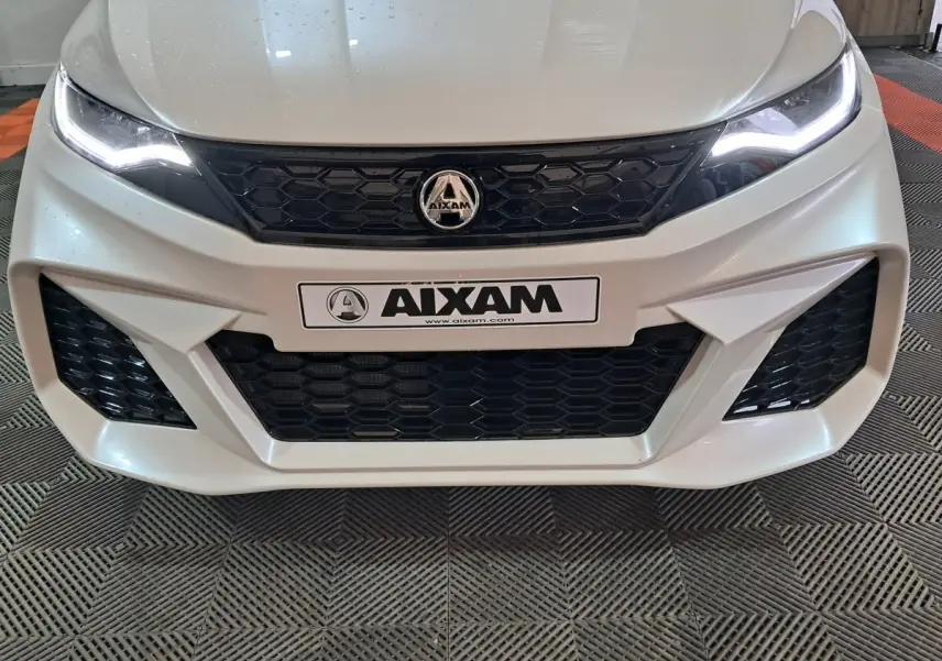 Vue frontale rapprochée de l'AIXAM AMBITION 0.5 CITY COUPE GTI blanche avec calandre noire et phares LED allumés.