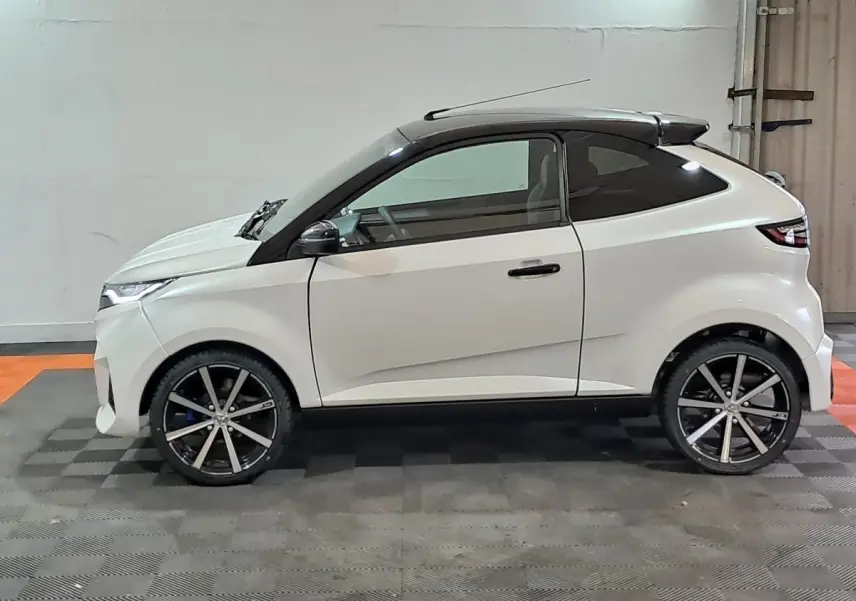 Profil droit de l'AIXAM AMBITION 0.5 CITY COUPE GTI blanc, avec jantes noires et toit noir contrasté.
