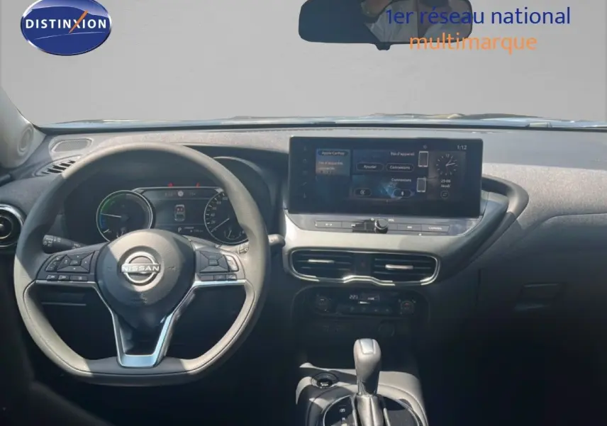 Vue intérieure frontale du tableau de bord du Nissan Juke Hybrid 2025 avec écran tactile et volant multifonction noir.