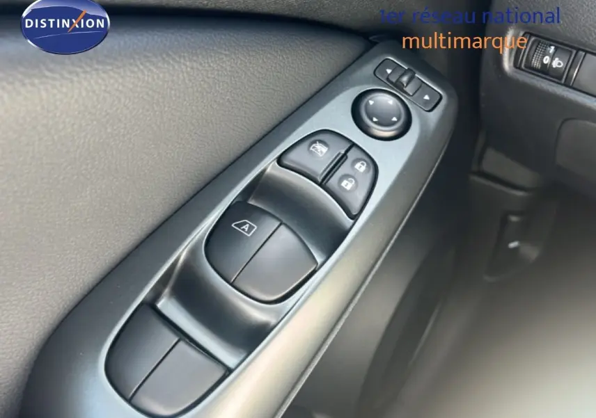 Gros plan sur les commandes de lève-vitres et rétroviseurs côté gauche intérieur d’un Nissan Juke gris Squale Metal 2025.