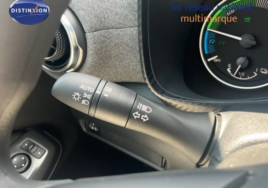 Gros plan sur la commande des feux et clignotants à gauche du volant du Nissan Juke hybride gris, avec tableau de bord partiel visible.