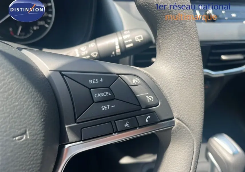 Gros plan sur les commandes à droite du volant gris clair du Nissan Juke Hybrid 2025, avec tableau de bord en arrière-plan.