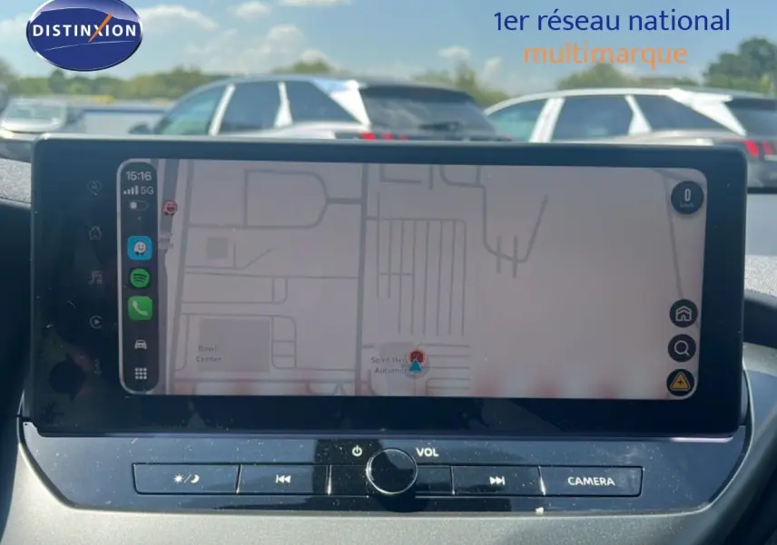 Vue intérieure du tableau de bord du Nissan Juke Hybrid 2025, écran tactile affichant la navigation, avec commandes audio en dessous.