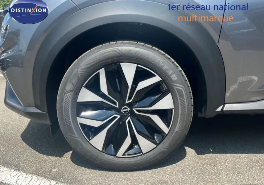 Gros plan sur la roue avant gauche du Nissan Juke gris squale métal, mettant en valeur la jante noire et argentée au design moderne.