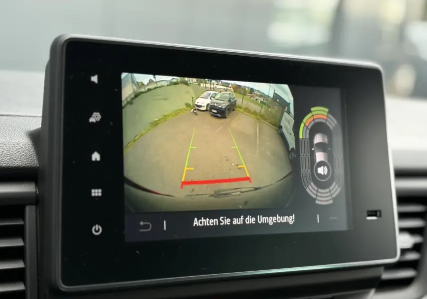 Écran tactile intérieur montrant la caméra de recul du Nissan Primastar Combi noir métal en stationnement.