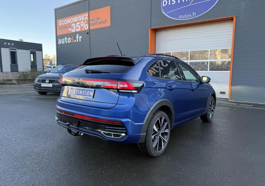 Volkswagen Taigo bleu récif métallisé en 3/4 arrière droit avec jantes noires brillantes et attelage amovible