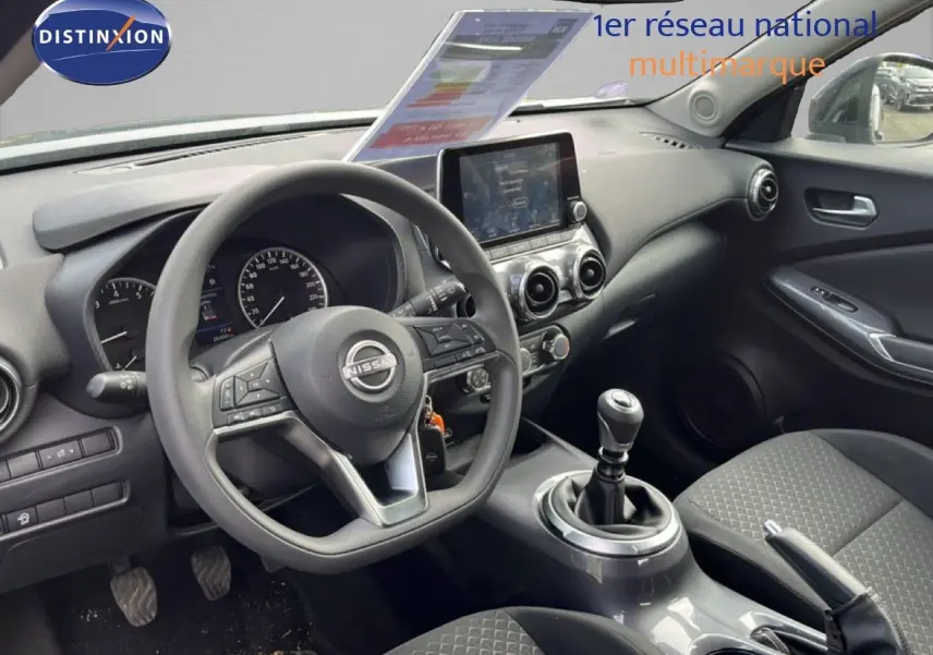 Vue intérieure côté conducteur du Nissan Juke noir métal 2023, mettant en valeur le volant multifonction et la console centrale moderne.