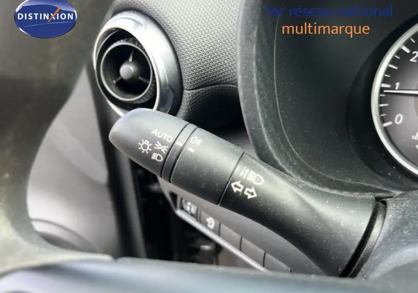 Gros plan sur la commande des phares et clignotants côté gauche du tableau de bord noir du Nissan Juke 2023.