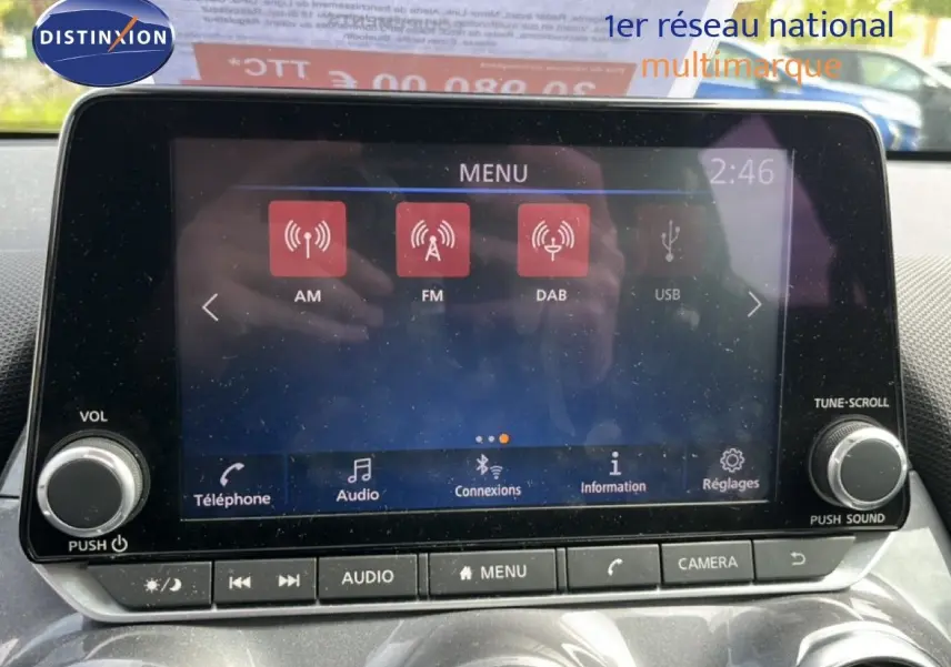 Vue intérieure centrée sur l’écran tactile multimédia du Nissan Juke 2023, avec commandes audio et climatisation visibles.