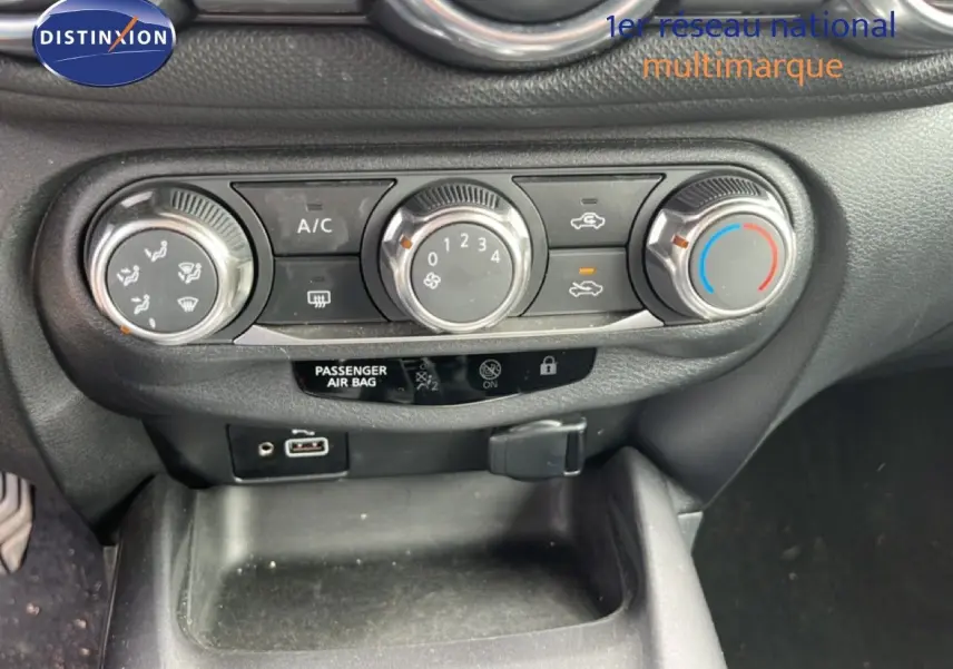 Gros plan sur les commandes de climatisation du Nissan Juke noir métal 2023, avec boutons rotatifs et affichage digital.