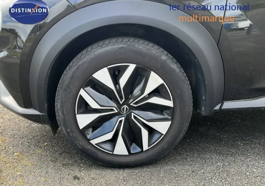 Gros plan sur la roue avant gauche du Nissan Juke noir métal 2023 avec jante alliage au design moderne.