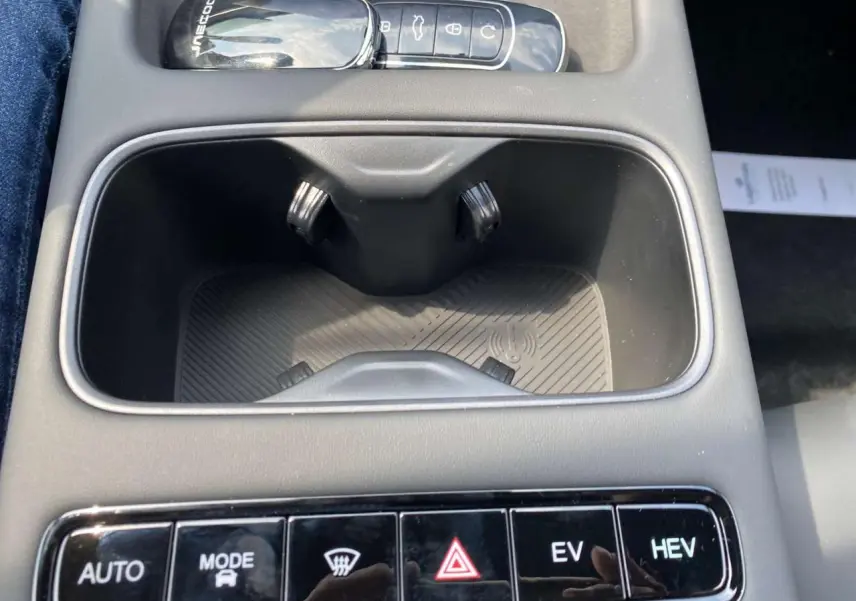 Gros plan sur la console centrale du JAECOO J7 blanc khaki, avec boutons de mode de conduite et recharge sans fil.