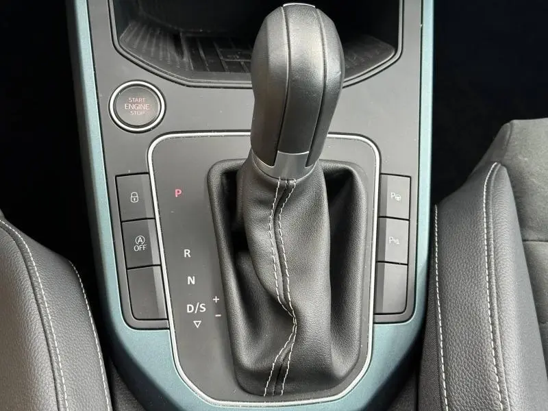 Gros plan sur le levier de vitesse automatique en cuir noir de la SEAT Arona 2025, entouré de commandes et console gris métallisé.