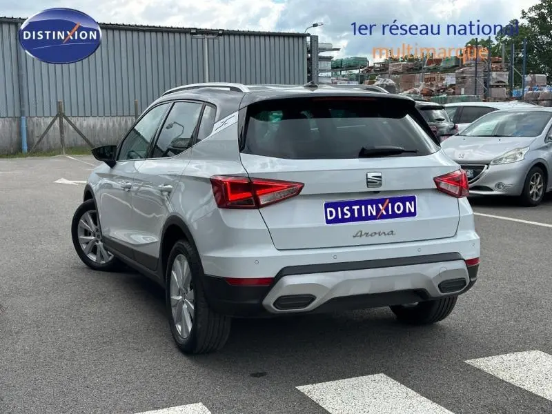 Vue 3/4 arrière droite d'un SEAT Arona blanc Nevada avec toit noir Minuit, jantes alu et feux arrière LED.