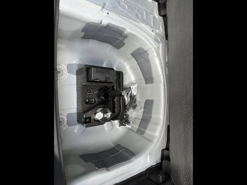 Vue plongeante sur le rangement sous siège arrière d'une SEAT Arona 2025 blanc Nevada métal avec accessoires de bord.