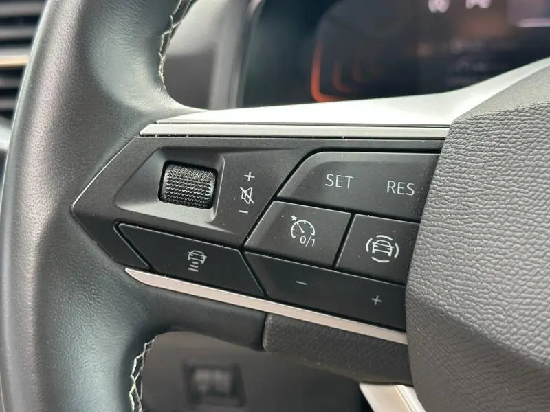 Gros plan sur les commandes multifonctions du volant cuir du SEAT Arona 2025, côté gauche, finition noire.