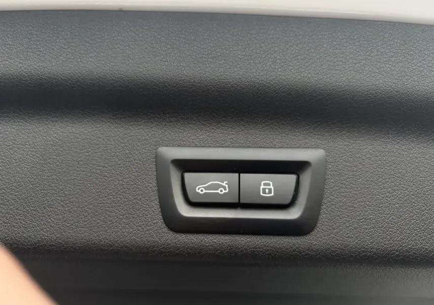 Gros plan sur les boutons d'ouverture et de verrouillage du hayon intérieur d'un BMW X1 blanc Mineral.