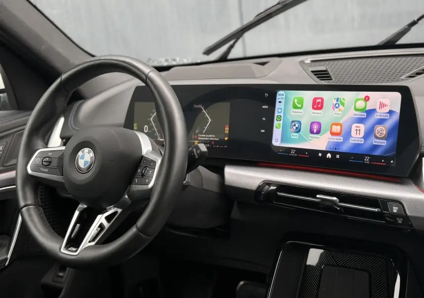 Vue intérieure du tableau de bord et volant cuir noir du BMW X1 sDrive 20d 2025 avec écran tactile incurvé.