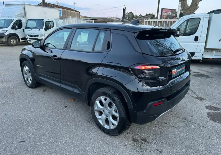 Vue 3/4 arrière droite d'un Jeep Avenger noir 2025 avec jantes alliage 17 pouces et feux arrière LED allumés.