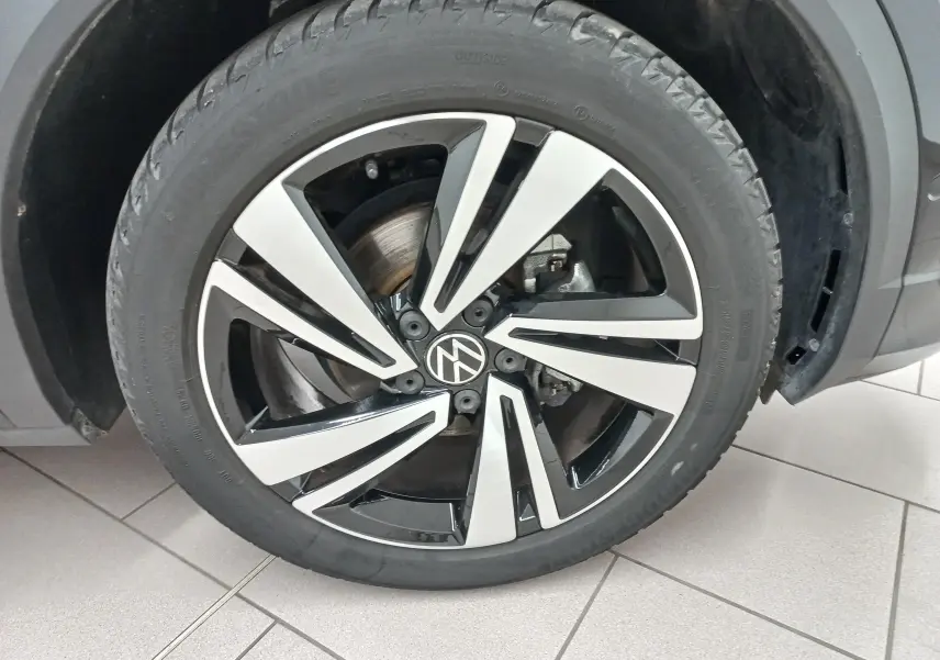 Gros plan sur la jante alliage bicolore noire et argent du Volkswagen T-Roc 1.5 TSI 150 DSG7 R-Line noir intense nacré.