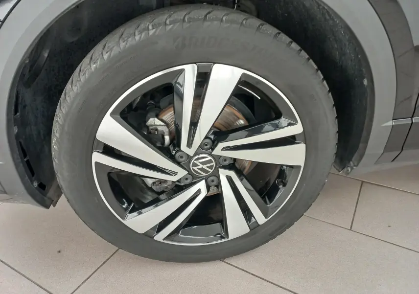 Gros plan sur la roue avant droite du Volkswagen T-Roc 1.5 TSI 150 DSG7 R-Line noir intense nacré avec jante alliage bicolore.