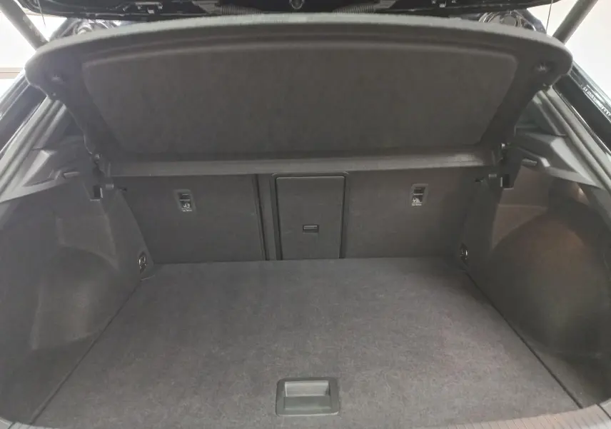 Coffre ouvert vu de l'arrière d'un Volkswagen T-Roc 1.5 TSI 150 DSG7 R-Line noir intense nacré, espace de chargement vide.