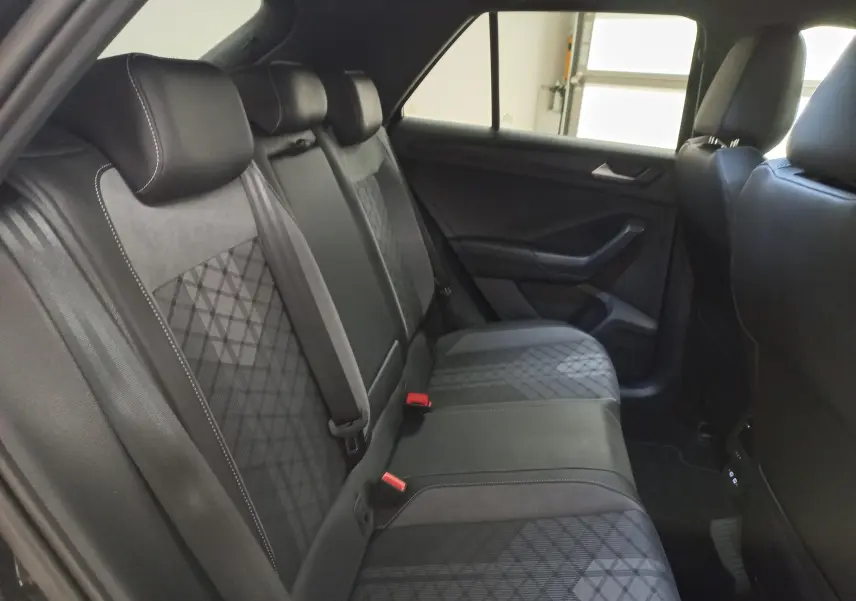Vue intérieure côté droit des sièges arrière noirs avec surpiqûres et motifs géométriques du Volkswagen T-Roc 1.5 TSI 2025.