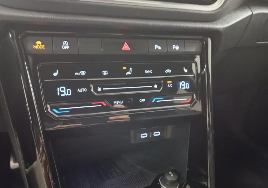Vue rapprochée de la console centrale du Volkswagen T-Roc 2025 noir intense, affichant la climatisation digitale à 19°C.