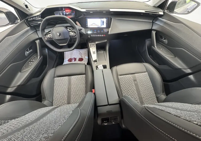 Vue intérieure avant de la Peugeot 308 2026 avec volant cuir multifonctions et écran tactile central.