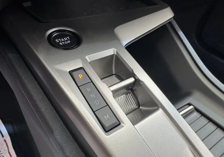 Gros plan sur la console centrale grise de la Peugeot 308 2026, avec bouton Start/Stop et commande de boîte auto.