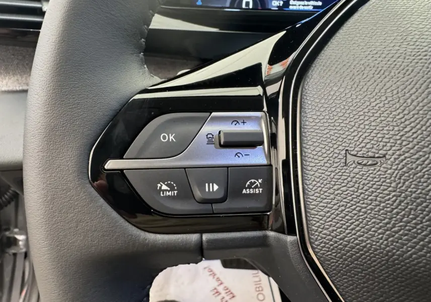 Gros plan sur le volant cuir gris de la Peugeot 308 2026, avec commandes multifonctions et régulateur adaptatif.
