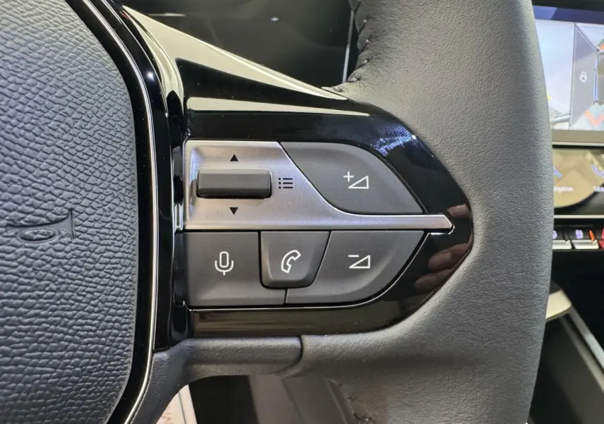 Gros plan sur le volant cuir multifonctions côté gauche de la Peugeot 308 gris clair avec commandes vocales et téléphone.