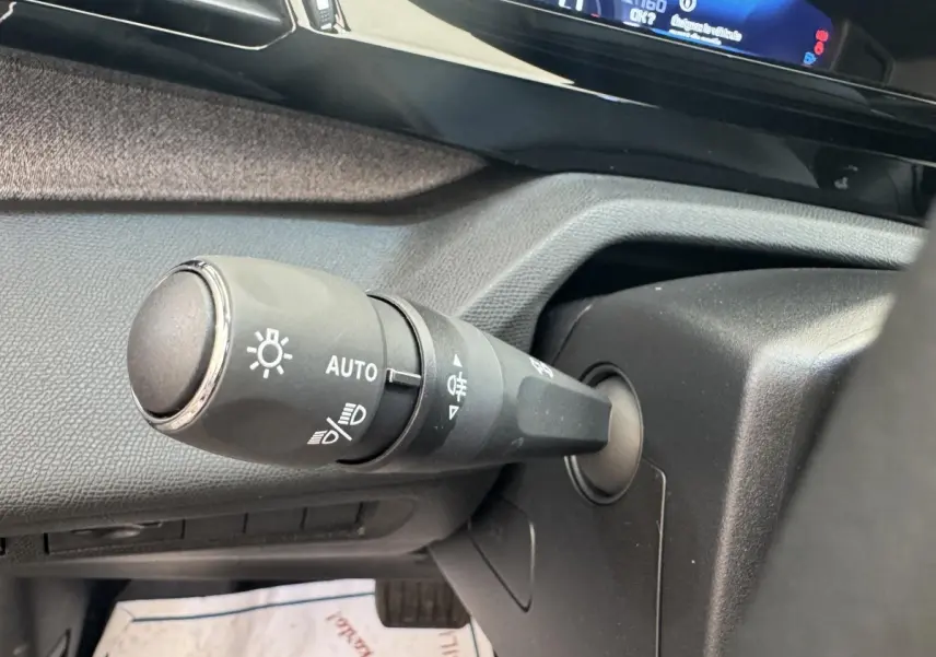 Gros plan sur la commande des phares avec réglage automatique dans l’habitacle gris d’une Peugeot 308 2026.