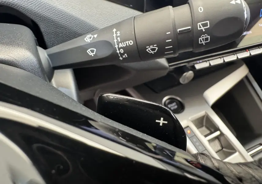 Gros plan sur la commande de lève-glace et palette de changement de vitesse côté gauche dans l’habitacle gris du Peugeot 308 2026.