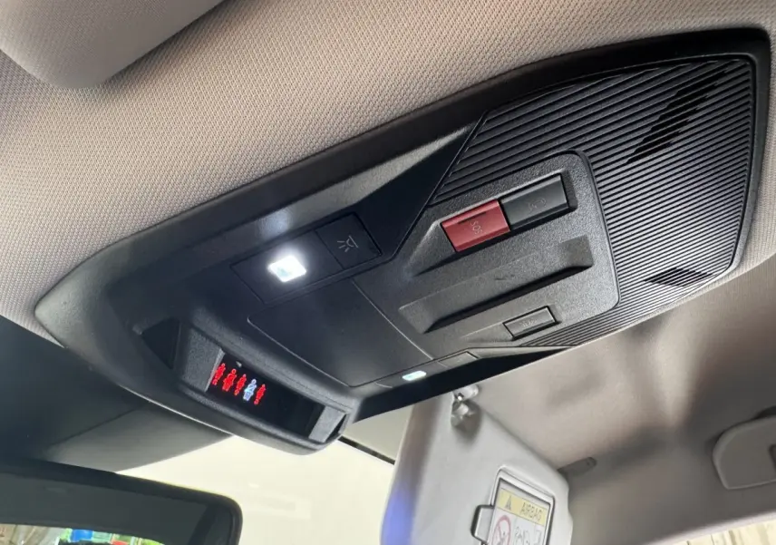 Vue en contre-plongée du plafonnier noir avec boutons SOS et éclairage intérieur de la Peugeot 308 gris clair.