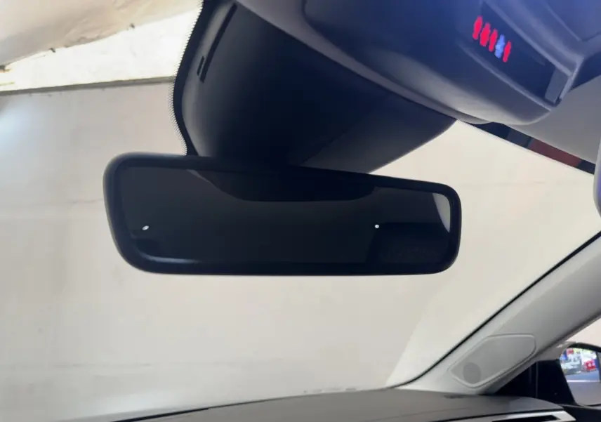 Vue intérieure centrée sur le rétroviseur intérieur d'une Peugeot 308 gris clair, avec pare-brise et partie du tableau de bord visibles.
