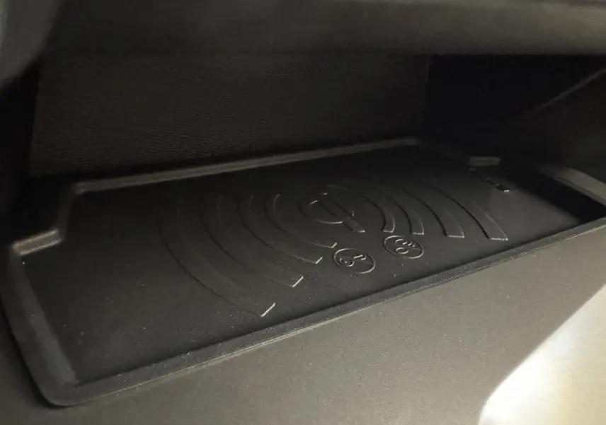 Gros plan sur le tapis de recharge sans fil noir dans la boîte à gants de la Peugeot 308 gris clair 2026.