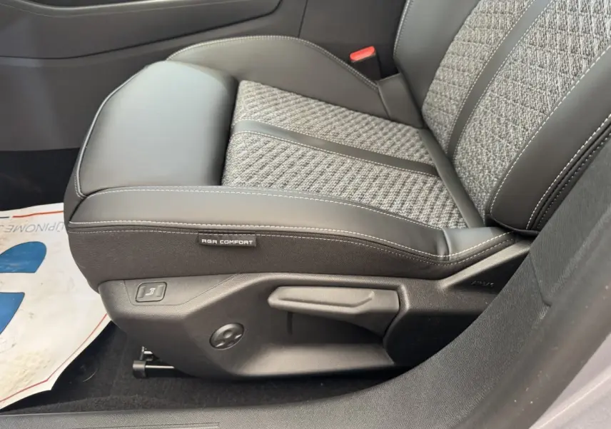 Gros plan sur le siège avant droit gris clair de la Peugeot 308 2026 avec étiquette AGR Comfort et commandes de réglage.