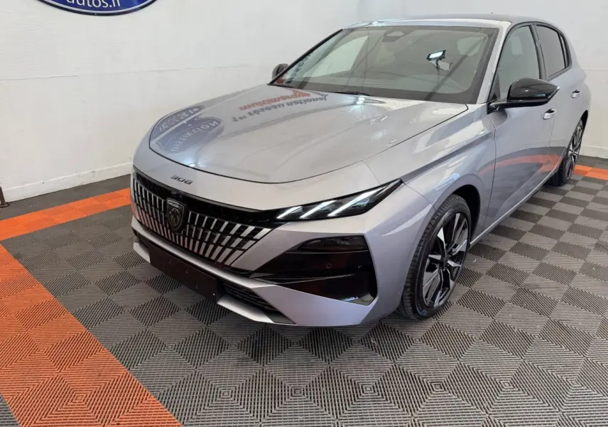 Peugeot 308 BlueHDi gris clair vue 3/4 avant droit, avec calandre distinctive et phares LED fins.