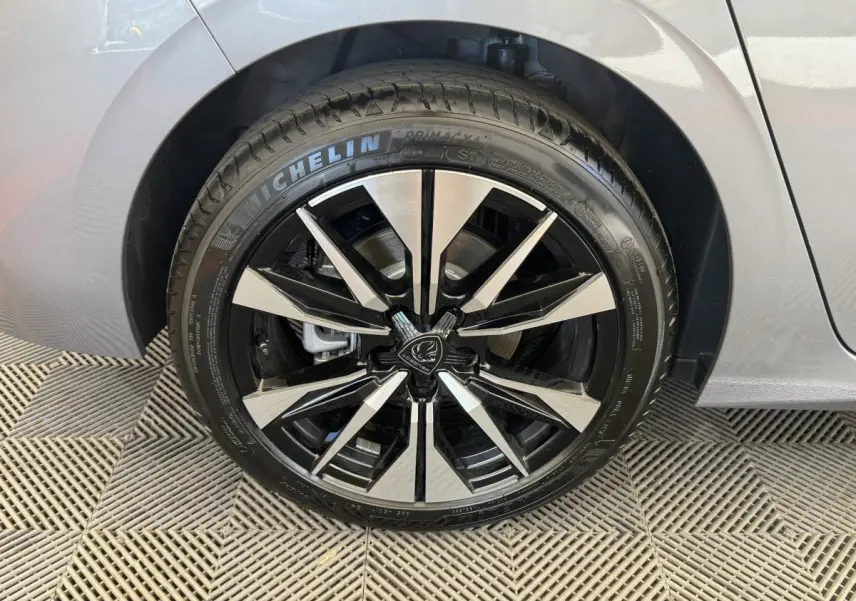 Gros plan sur la roue avant droite d’une Peugeot 308 gris clair, jante alliage noire et argentée design moderne.