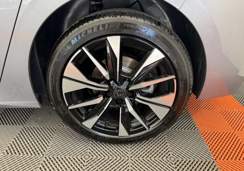 Gros plan sur la roue avant droite gris clair de la Peugeot 308 avec jante alliage noire et argentée distinctive.