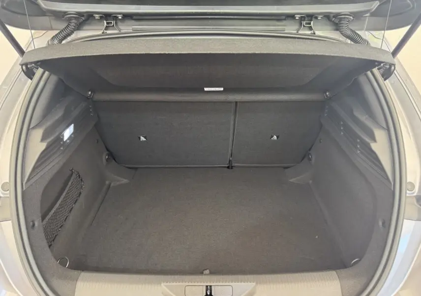 Vue intérieure du coffre ouvert de la Peugeot 308 gris clair, montrant l'espace de rangement et la banquette arrière rabattable.