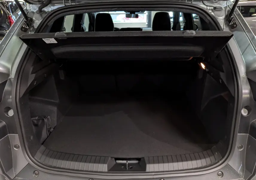 Coffre ouvert vu de l’arrière d’un Dacia Duster gris schiste 2026, montrant l’espace de chargement vide et la tablette cache-bagages.