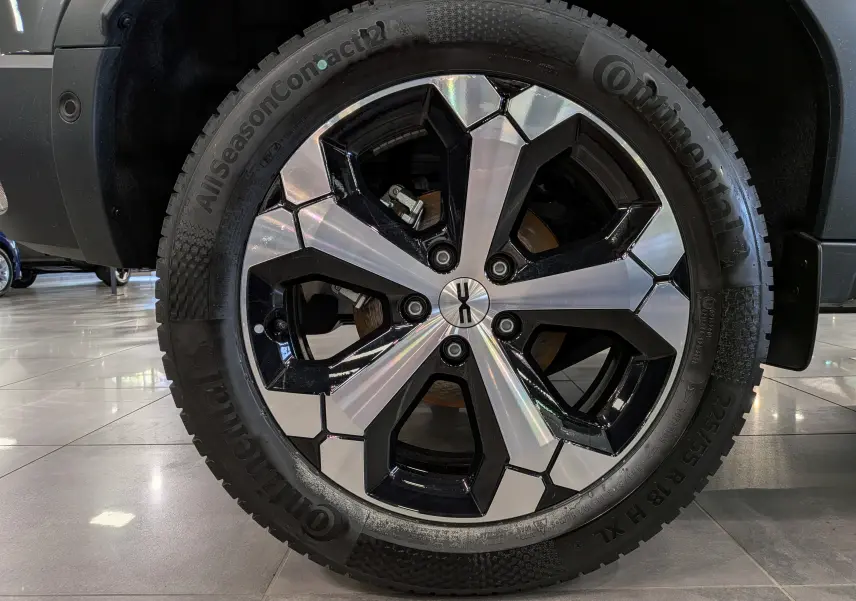 Gros plan sur la jante biton noire et argentée du Dacia Duster Hybrid-G 150 CH 4x4 gris schiste, vue côté gauche.
