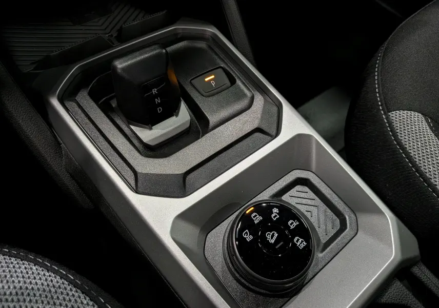 Gros plan sur la console centrale grise du Dacia Duster Hybrid-G 150 CH 4x4 2026, avec levier de vitesses automatique et sélecteur de modes de conduite.