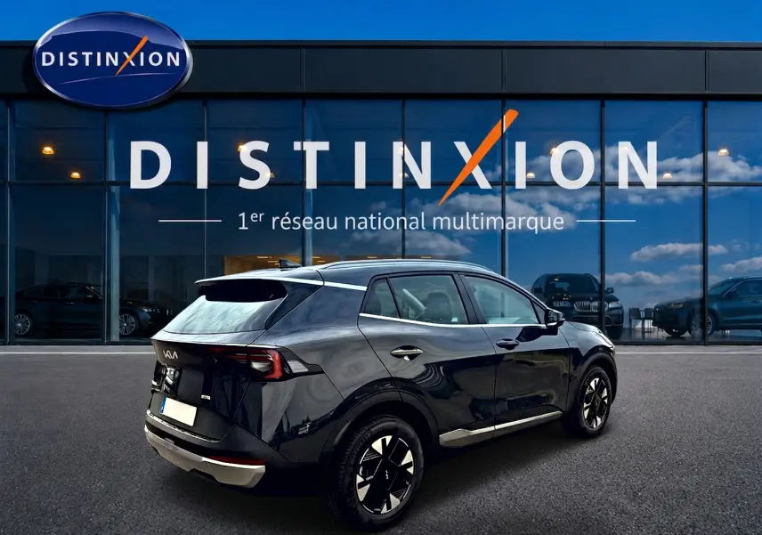 KIA Sportage 1.6 hybride gris eclipse vu en 3/4 arrière droit devant une concession Distinxion.