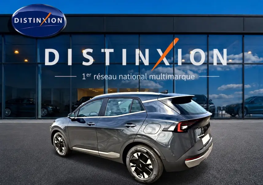 KIA Sportage 1.6 hybride gris eclipse vu en 3/4 arrière droit devant un showroom Distinxion.