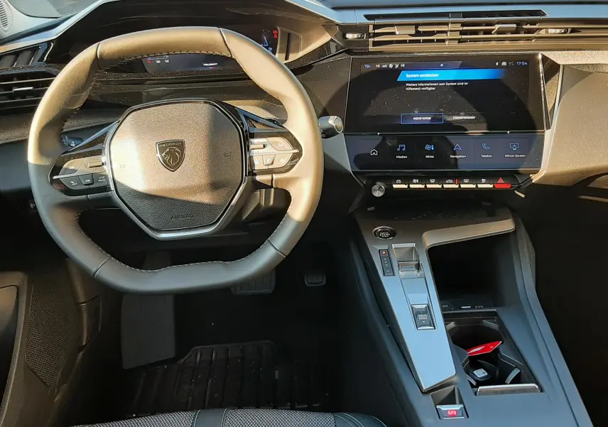 Vue intérieure avant du poste de conduite de la Peugeot 308 Bleu Obsession avec volant compact et écran tactile central.