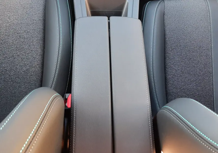 Vue plongeante sur la console centrale et les sièges noirs avec surpiqûres bleues du Peugeot 308 Bleu Obsession 2025.