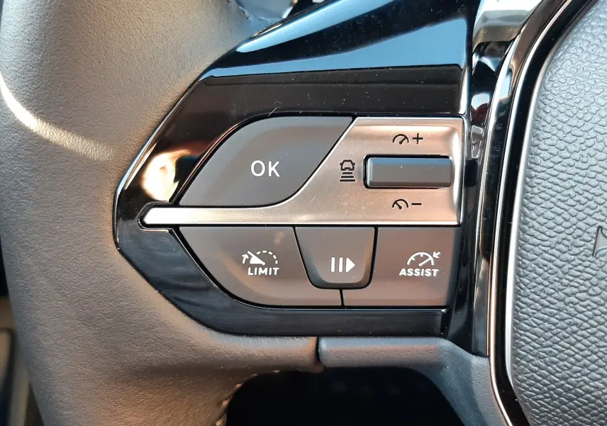 Gros plan sur les commandes au volant côté gauche d'une Peugeot 308 2025, finition noire avec boutons multifonctions.